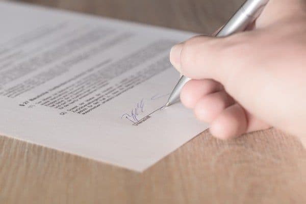 Plano detalle de persona firmando un contrato laboral.