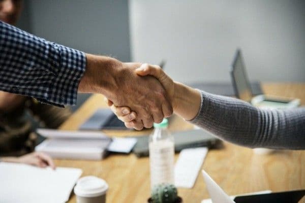Empleador de empresa principal y empleador de empresa contratista estrechando sus manos.