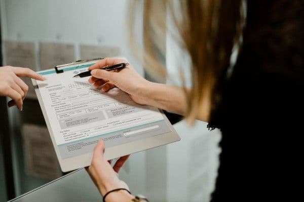 Primer plano de mujer sosteniendo un formulario para antes de completarlo.