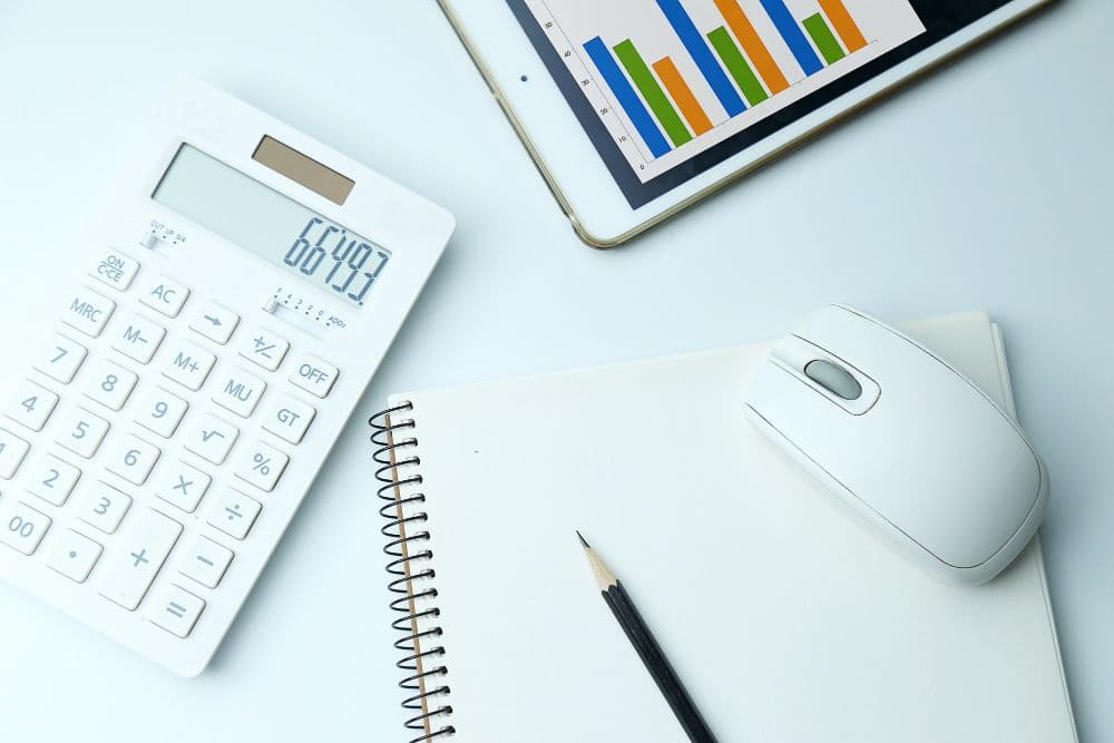 Calculadora junto a tablet con gráficos posados sobre un escritorio.