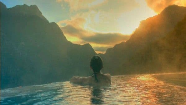 Mujer disfrutando de sus días de vacaciones por año en una piscina termal durante un atardecer.