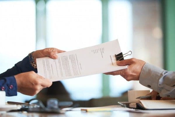 Primer plano de personas pasando un documento de descanso médico.