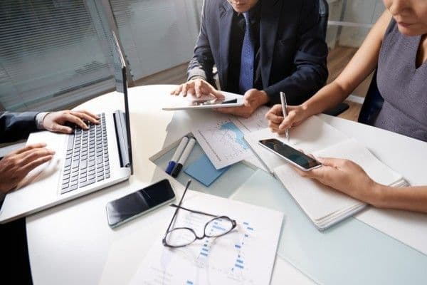 Personas de negocio trabajando en conjunto en un escritorio grande.