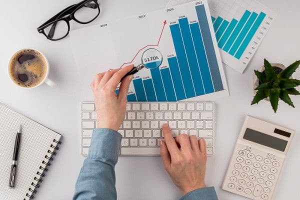Personal de recursos humanos analizando tabla de crecimiento con una lupa.