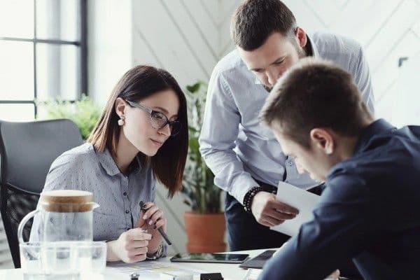 tres trabajadores de una oficina analizan documentos de trabajo.
