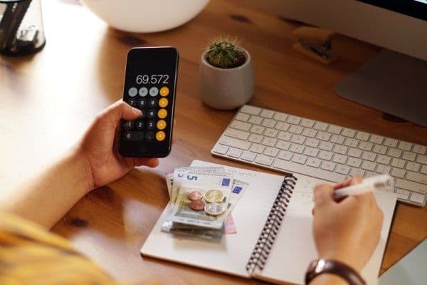 Profesional de recursos humanos realizando un cálculo de dinero en su celular.