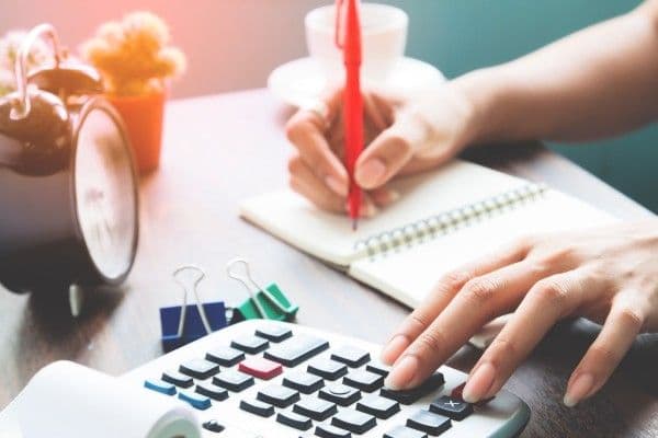 mujer realizando el cálculo de horas extras en una calculadora.