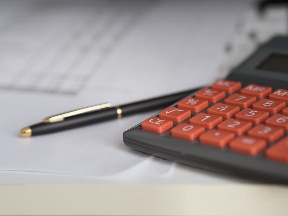 Calculadora y bolígrafo sobre un escritorio.