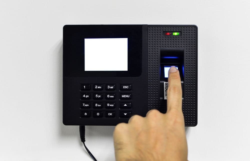 Persona marcando su huella dactilar en un control de asistencia tipo reloj checador.