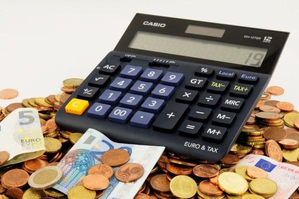 Calculadora junto a monedas y billetes sobre una mesa.