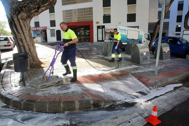 Dos empleados de limpieza trabajando en una calle.