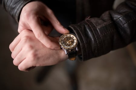 Primer plano de persona tomando su reloj de pulsera, simbolizando la puntualidad.