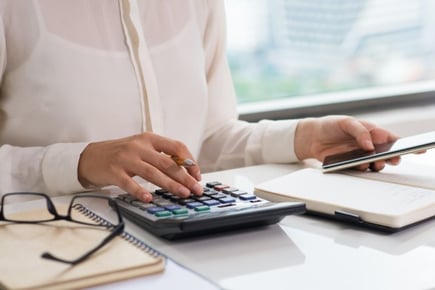 Mujer realizando un cálculo de sueldo sin software de remuneraciones sino que con calculadora.