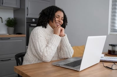 Mujer joven trabajando desde su casa con una laptop.