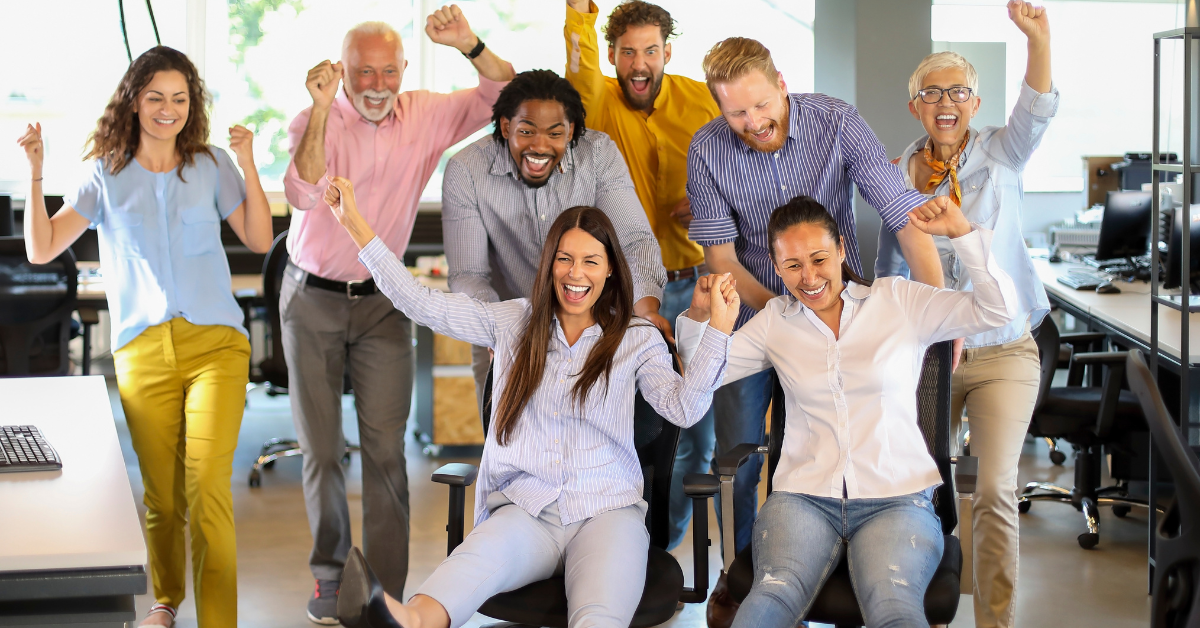 Grupo de colaboradores celebrando juntos en la oficina, transmitiendo alegría, trabajo en equipo y bienestar laboral.
