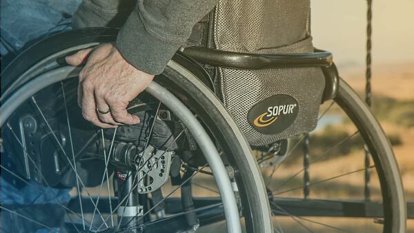 Primer plano de persona mayor en silla de ruedas.