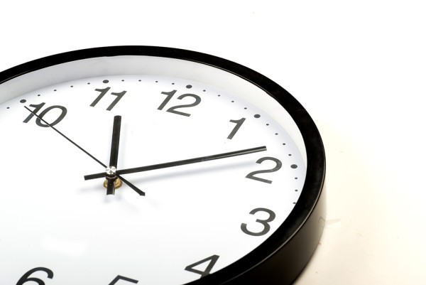Reloj de color blanco puesto sobre una mesa marcando las 11:10 horas.