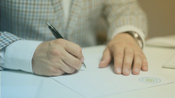 Primer plano de persona firmando un anexo de contrato.