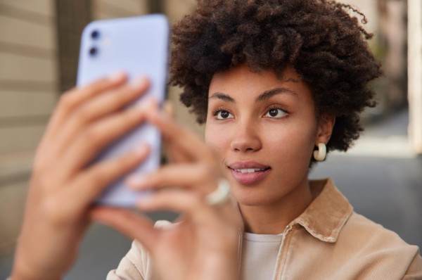Mujer joven utilizando la cámara de su celular para el reconocimiento facial.