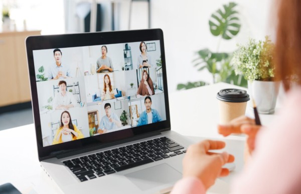 Mujer conectada a videoconferencia con otras 9 personas en su laptop.